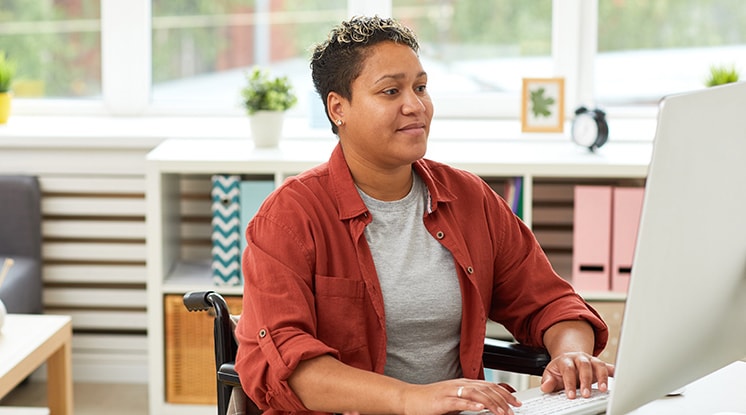 Persona con camisa roja mirando hacia la derecha en la computadora