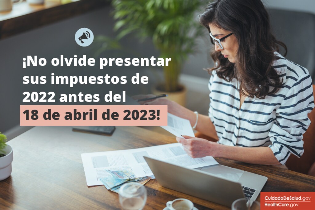 ¡No olvide presentar sus impuestos de 2022 antes del 18 de abril de 2023! Una mujer con suéter a rayas se sienta en su computadora portátil con documentos fiscales en la mano.