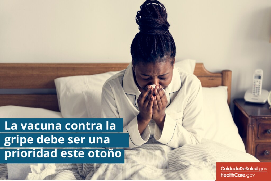 {Haga que vacunarse contra la gripe sea una prioridad este otoño} Imagen: {Mujer enferma estornudando en la cama}